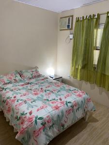 a bedroom with a bed with a floral comforter and a window at Kitnet das Dunas in Garopaba