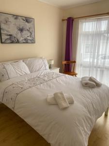 Un dormitorio con una cama blanca con toallas. en Cozy seaside home,3 minute walk to village/beach, en Lahinch