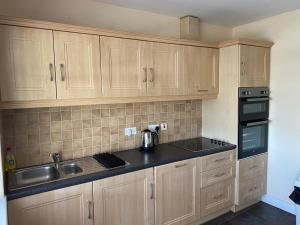 a kitchen with wooden cabinets and a sink and stove at Cozy seaside home,3 minute walk to village/beach in Lahinch