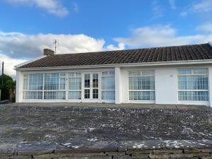 a white house with windows and a roof at Cozy seaside home,3 minute walk to village/beach in Lahinch