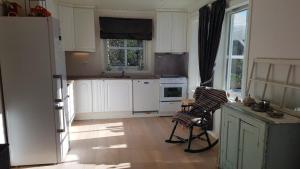 a kitchen with white cabinets and a white refrigerator at Slåta - The Dragon-valley cabin in Lyngdal