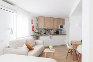 a white living room with a white couch and a kitchen at Dolphin Rentals Feria de Madrid in Madrid