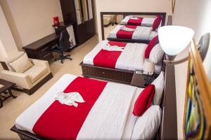 Cette chambre comprend 3 lits avec des draps rouges et blancs. dans l'établissement La Pepiniere Hotel, à Pétionville