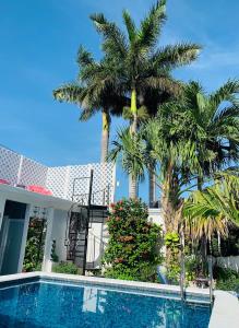 a swimming pool in front of a house with palm trees at The Quetzal in Cancún