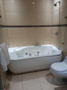 a bathroom with a white tub and a toilet at Hotel Ines Maria in Cuenca