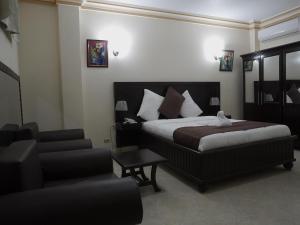 une chambre d'hôtel avec un lit et une chaise dans l'établissement La Pepiniere Hotel, à Pétionville