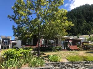 a house with a tree in the front yard at Hampshire Holiday Parks - Queenstown Lakeview in Queenstown