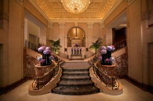people are sitting in a large room with ornate staircases at The Peninsula New York in New York