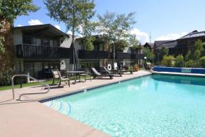 a swimming pool with chairs and a table and a house at Lichenhearth 26 in Snowmass Village