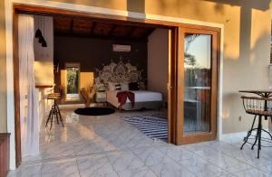 a bedroom with a bed and a door leading to a patio at Chalés Pura Vida in Itacaré