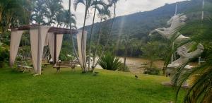 un parque con un banco y un cenador en el césped en Aparts -Hotel Cavalinho Branco, en Águas de Lindóia