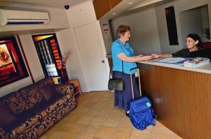 a man standing at a counter in a waiting room at Summit Motel in Townsville