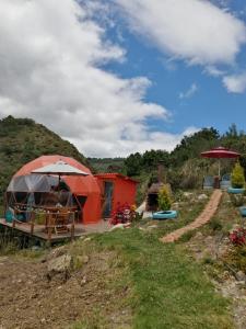 een yurt met een tafel en een paraplu op een heuvel bij Glamping Cabaña San Martin in Guatavita