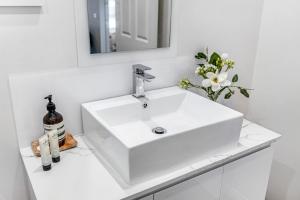 a white bathroom with a sink and a mirror at Wotama, Macedon B and B, Honour Ave, Mount Macedon in Mount Macedon