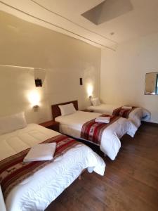 three beds in a hotel room with at Hugos house in Cusco