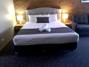 a bedroom with a large bed and a blue chair at Kerang Motel in Kerang