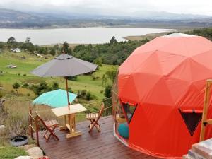 a tent on a deck with chairs and an umbrella at Glamping Cabaña San Martin in Guatavita