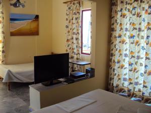a room with a tv and a bed and a window at Irini Studios in Plomari