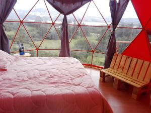 a bedroom with a large window with a bed and a chair at Glamping Cabaña San Martin in Guatavita