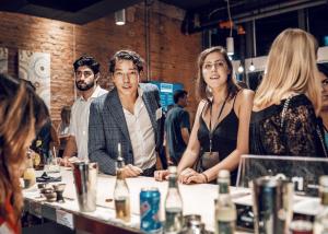 a group of people standing around a bar at SOVA Micro-Room & Social Hotel in Dallas