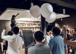 un grupo de personas de pie en una multitud con globos en SOVA Micro-Room & Social Hotel, en Dallas