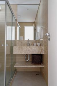 Un baño con lavabo y ducha de cristal. en Casa maravilhosa na praia de Muro Alto - Porto de Galinhas, en Porto de Galinhas