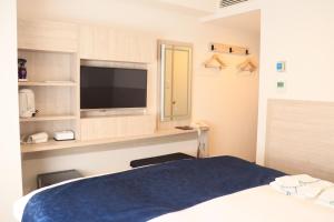a hotel room with a bed and a television at Hotel Rose Garden Shinjuku in Tokyo