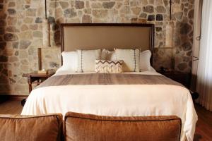 1 dormitorio con 1 cama grande y pared de piedra en Hotel Boutique Los Pasos & Spa en Antigua Guatemala