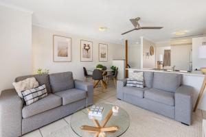 a living room with two couches and a kitchen at Coolum Beach Getaway Resort in Coolum Beach
