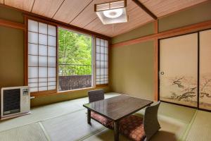 a dining room with a table and chairs and a window at Yama no Yado Meiji Onsen in Chino