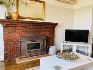 a living room with a fireplace and a tv at Daisy Cottage on Duke 3BR in Yarram