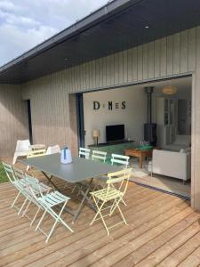 eine Terrasse mit Tisch und Stühlen auf einem Deck in der Unterkunft Maison Les Dunes Bourgales in Gouville-sur-Mer