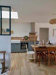 a kitchen with a wooden table and a dining room at Villa des Dunes in Gouville-sur-Mer