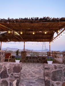 a stone patio with a pergola and a table with plants at Algor Farm in Qūr