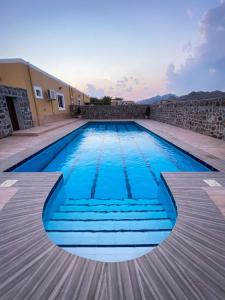 a swimming pool with blue water in front of a building at Algor Farm in Qūr