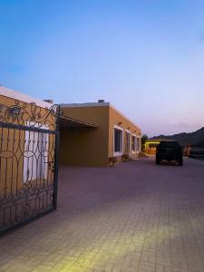a car parked in front of a building with a gate at Algor Farm in Qūr