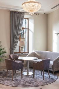 uma sala de estar com um sofá, uma mesa e cadeiras em CALVARY Hotel & Restaurant Vilnius em Vilnius
