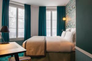 a bedroom with a bed with green curtains and a window at Hôtel Edouard 6 by Malone in Paris