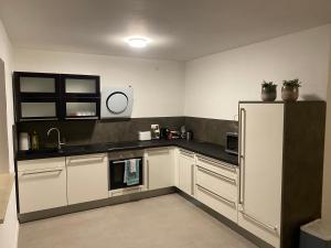 a kitchen with white cabinets and a stainless steel refrigerator at Vogelnest in Windorf