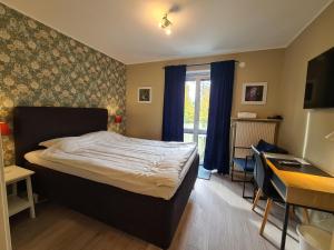 a bedroom with a bed and a desk and a window at Hotell BOULOGNE in Gävle