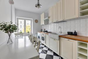 uma cozinha com armários brancos e um piso xadrez preto e branco em Downtown Apartments Old Town View - Green Gate em Gdansk