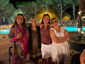 four women posing for a picture in front of a pool at Camping Village Punta Navaccia in Tuoro sul Trasimeno