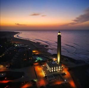 a lighthouse on a beach at night with the ocean at Bungalow Elegance in Maspalomas