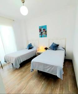 two beds in a room with a wooden floor at Maravilloso apartamento in Nerja