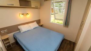 a small bedroom with a blue bed and a window at CAMPING AZU'RIVAGE in Azur +35 photos