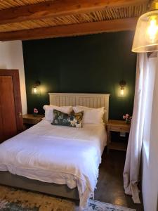 a bedroom with a white bed with a green wall at Vineyard Cottage at Bosman Wines in Wellington