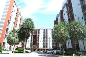 a parking lot with palm trees in front of a building at Similan Mansion in Bangsaen