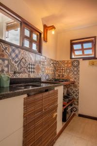 uma cozinha com azulejos na parede e um balcão em Apartamentos Quintal - 2 Quartos Suítes e Sala em Morro de São Paulo