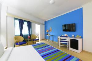 Peerless Resort Port Blair في Shādipur: غرفة نوم زرقاء مع سرير ومكتب