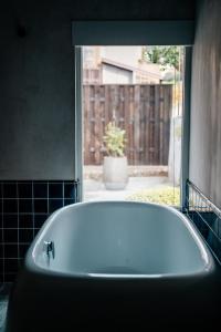 a white bath tub in a bathroom with a window at Bed and Craft TATEGU-YA in Nanto
